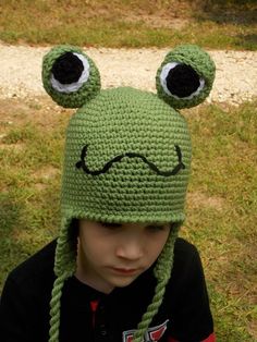 a young boy wearing a crocheted frog hat