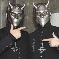 two men in black jackets with horns on their faces and one pointing at the camera