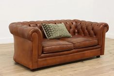 a brown leather couch sitting on top of a hard wood floor