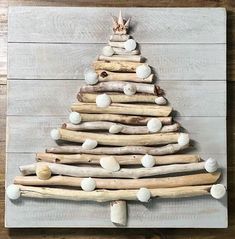 a christmas tree made out of driftwood on a wooden board with white balls around it