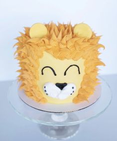 a lion cake with yellow icing on top of a glass plate and white background