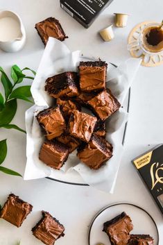 chocolate brownies on a plate next to a cup of coffee and some tea leaves