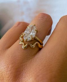 a woman's hand with a gold ring and a white diamond in the middle