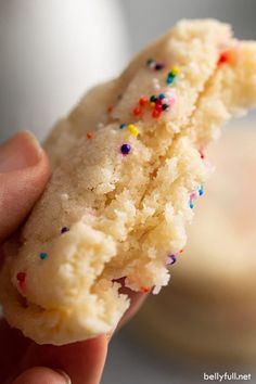 a hand holding a half eaten sugar cookie with sprinkles