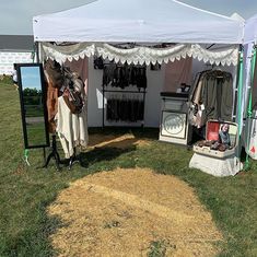 an open tent with clothes hanging on the wall and other items in front of it