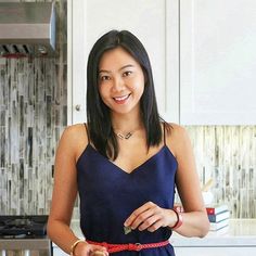 a woman in a blue dress is holding a knife and cutting vegetables on a board