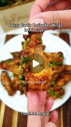 a person holding up a piece of food on a plate with the caption crispy garlic cord wings in air fryer