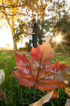 a couple standing next to each other in front of a leaf with the words save the date written on it