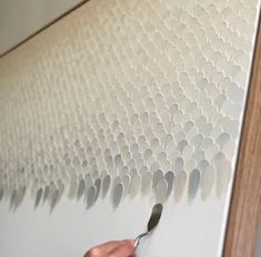 a person is using a paint brush to paint a wall with white circles on it