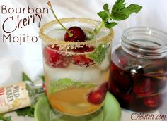 a glass filled with ice and cherries on top of a green plate