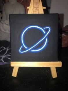 an easel with a painting on it that has the saturn symbol painted on it