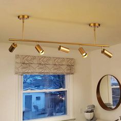 three lights are hanging from the ceiling above a sink in a bathroom with a window