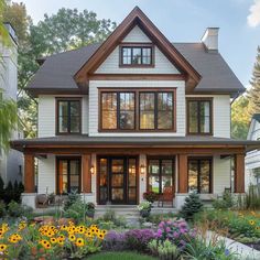 a large white house with lots of windows and flowers in the front yard, on a sunny day