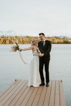 A bride in a two-piece sleeveless wedding gown cheering while her groom pops a bottle of champagne on a dock over a lake Wedding Day Poses, Instagram Makeup Artist, Photographer Content, Gown Rental, Alaska Wedding, Photography Workshop