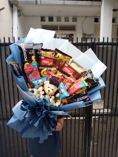 a person holding a bunch of candy and candies in front of a black fence