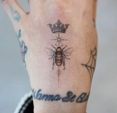 a woman's hand with a bee and crown tattoo on it