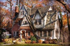 an old house in the fall with lots of leaves on the ground and trees around it