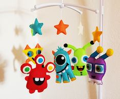 three colorful stuffed animals hanging from a white hook with stars on the wall behind them