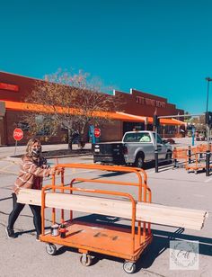 a woman pushing a cart with a wooden bench on it in front of a store