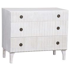 a white dresser with three drawers and two knobs on the front, against a white background