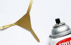 a can of spray paint next to a gold kangaroo tail shaped object on a white surface