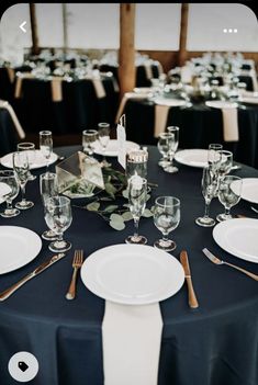 the table is set with white plates, silverware and place settings for an elegant dinner