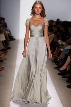 a woman is walking down the runway in a long dress with an off shoulder top