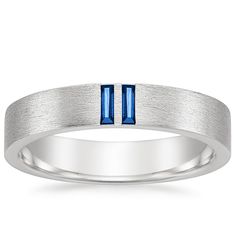 a white gold wedding band with blue sapphire stones in the center and two vertical stripes on each side