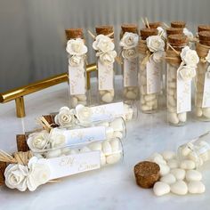 wedding favors in glass bottles with flowers and corks on the table next to each other