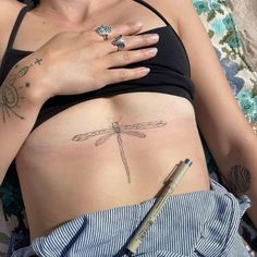 a woman with tattoos on her stomach is laying down and holding a pen in her hand