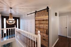 a wooden door is opened to reveal a hallway with white railing and wood flooring