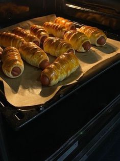 hotdogs and croissants are being cooked in the oven for consumption