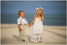 two young children holding hands on the beach