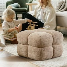 a woman sitting on the floor playing with a toddler who is holding a toy