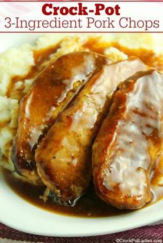 two pork chops covered in gravy on top of mashed potatoes