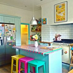 a kitchen with colorful stools in front of an island and refrigerator freezer behind it