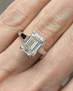 a woman's engagement ring with an emerald cut diamond