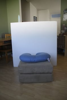 two pillows are stacked on top of each other in front of a large white wall