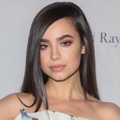 a close up of a person with long hair and wearing a white dress at an event