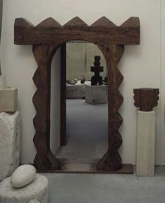 a large mirror sitting on the side of a wall next to vases and sculptures