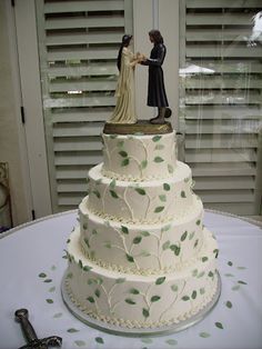 a wedding cake with figurines on top is displayed in front of shutters