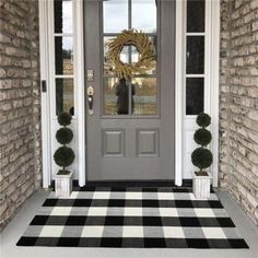 a gray front door with a black and white checkered rug on the floor next to it