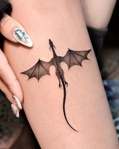 a woman's leg with a tattoo that has a dragon on it