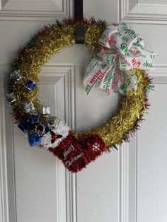 a christmas wreath on the front door with candy canes and tinsel wrapped around it