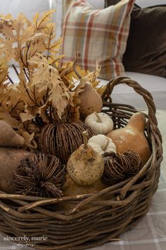 a wicker basket filled with gourds and pumpkins on top of a table