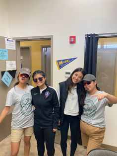 four young women posing for the camera in front of a door with signs on it