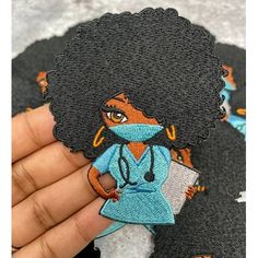 a person holding a small patch with an image of a woman in scrubs on it