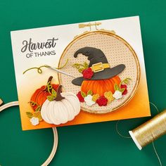 a card with a pumpkin and witch's hat on it next to some spools of thread