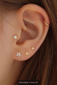 a woman's ear with three small stars on the top and one smaller star in the middle