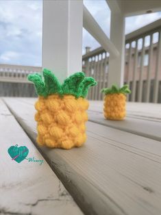 two small knitted pineapples sitting on top of a wooden table next to each other